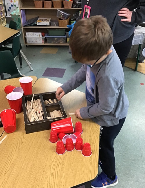 Child choosing craft sticks and cups.