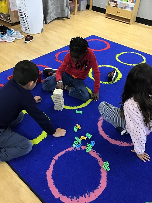 Children playing a building game on the carpet.