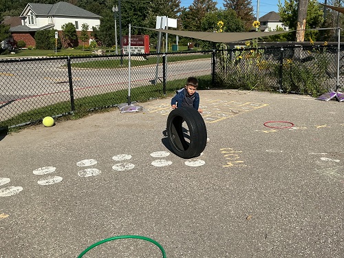 CHild rolling a tire.