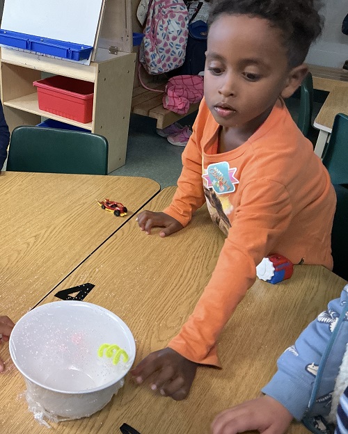 Child putting pipe cleaner on a bowl