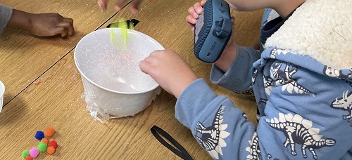 Child holding the speaker up to the bowl.