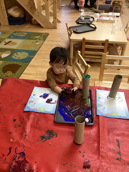Child painting with paper towel rollers