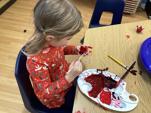 A school age child painting an egg carton poppy