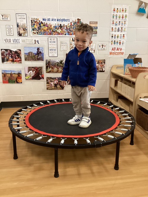 A preschool child jumping on an indoor trampoline