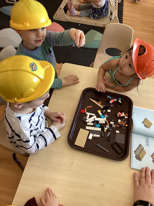 A group of preschool children sitting at a table building with lego