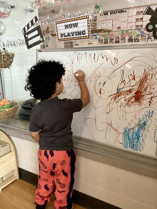 A preschool child using a white board to create a "movie"
