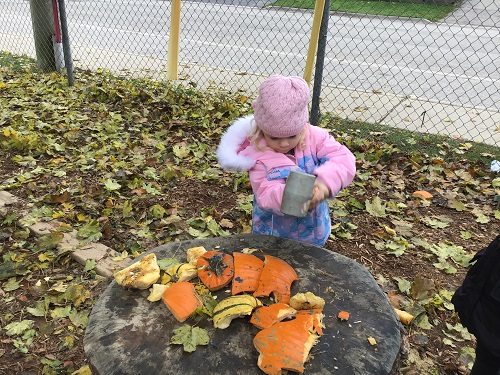 Preschool using a hammer to smash pumpkin