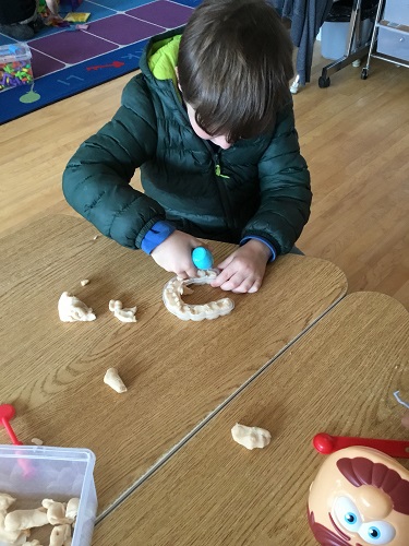 school age child manipulating playdough while sitting at a table. 
