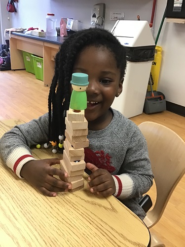 child smiling while presenting a tower she built