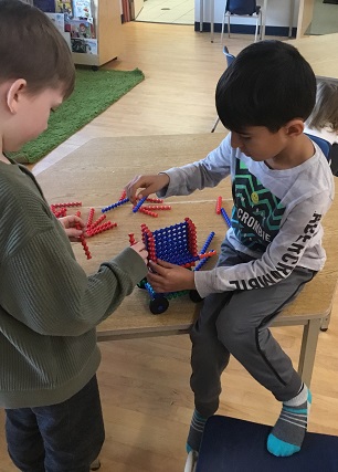 2 children building at rectangular structure using groved coloured structures. 