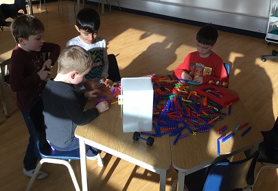 group of school age childre using  groved coloured dowels to stack 