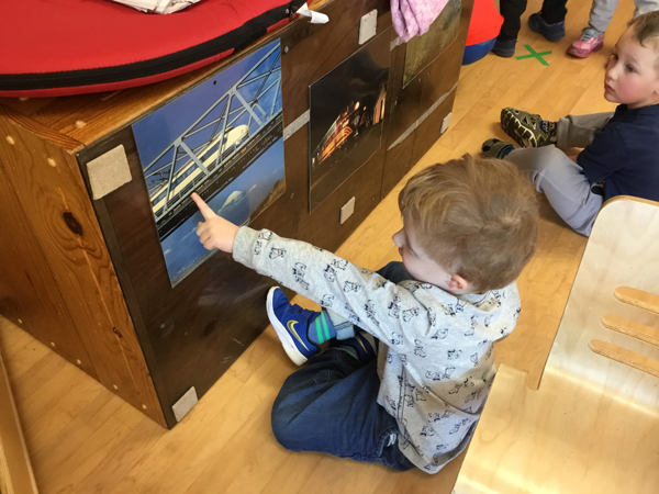 Boy pointing to a picture of a train on a bridge