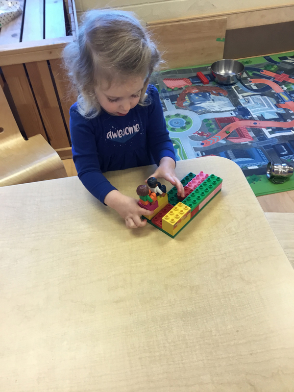 child buidling a train with LEGO