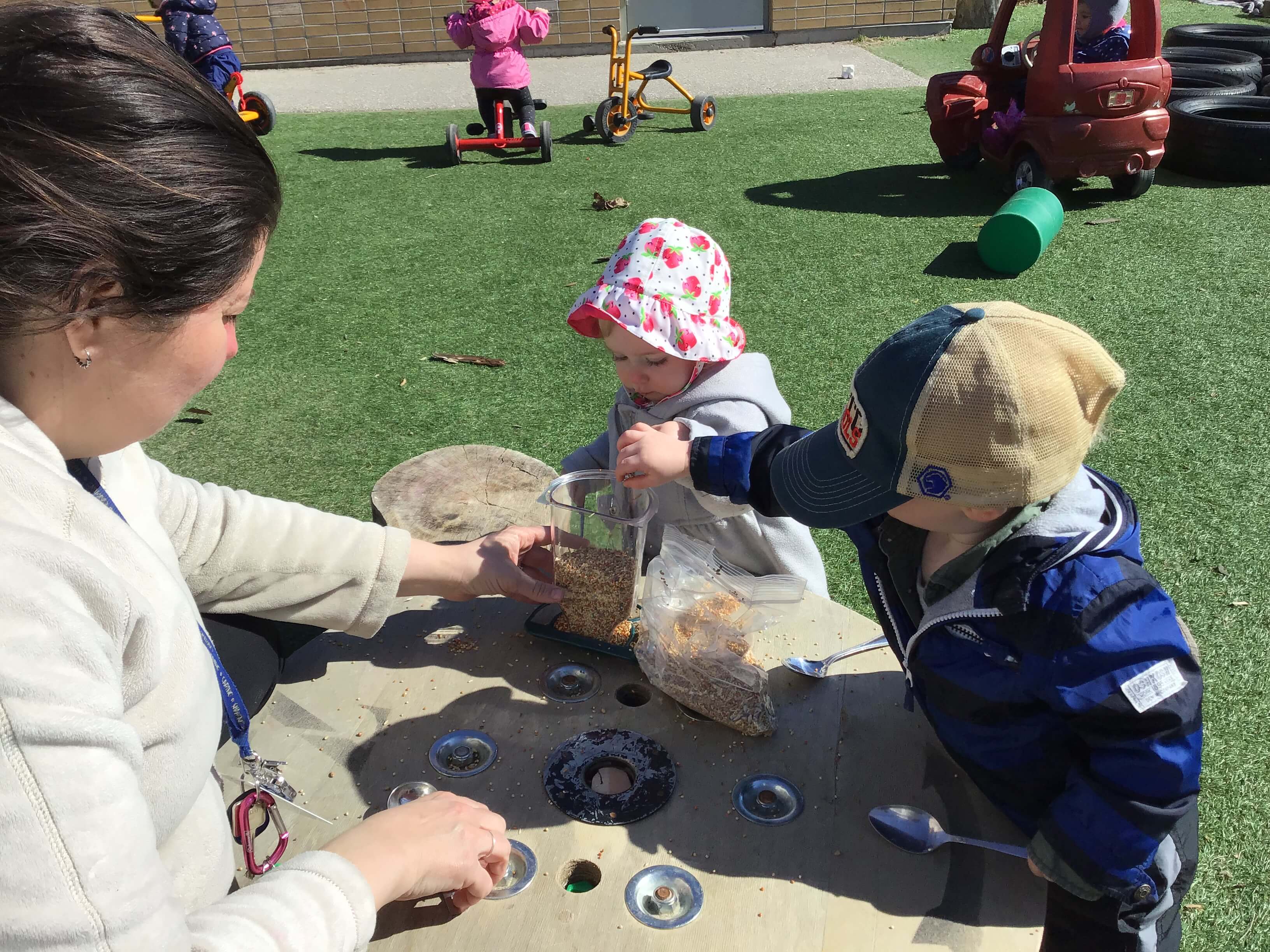 children filling a bird feeder with seeds