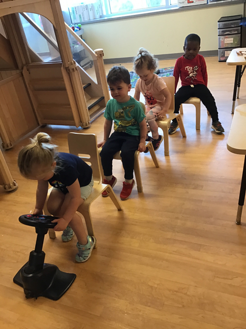 kids sitting on chairs in a line pretending to drive