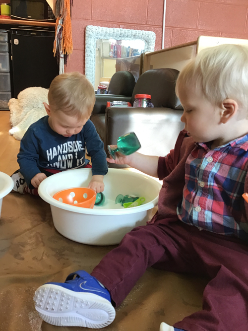 two children playing on the floor with some toys