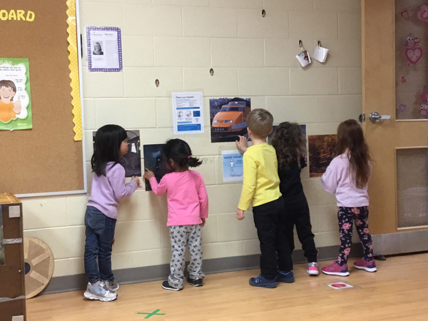 children looking at pictures of trains on a wall