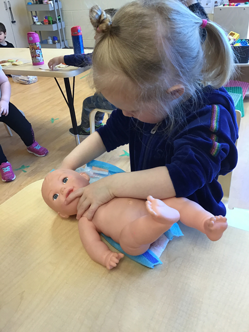 Girl changing a baby doll's diaper