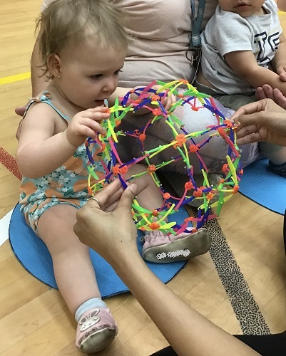 An infant pulling open a strechy ball
