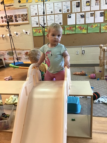 Child climbing up to the top of a slid to slid down