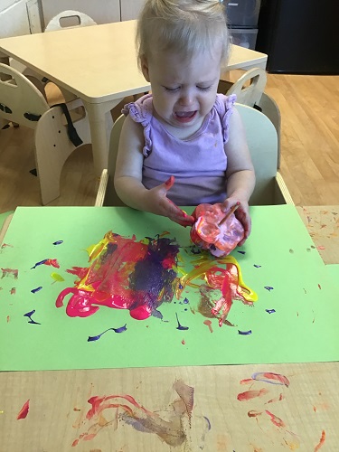 A child touching paint and looking very sad