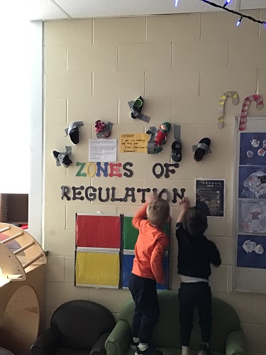 Two children trying to reach the shoes that have been duct taped to the wall