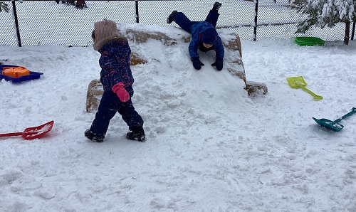 A child slidding down a snow pile up