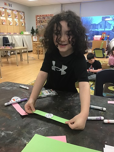 A child showing their paper watch creation
