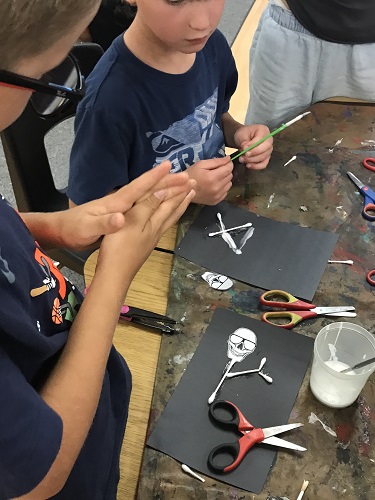 Children creating a skeleton craft with cotton swabs and cut outs