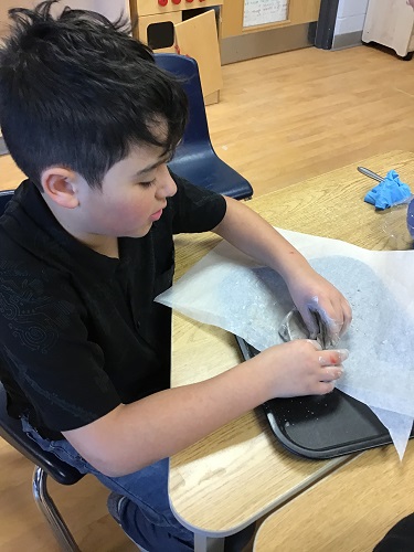 A child molding clay into a bowl with their fingers