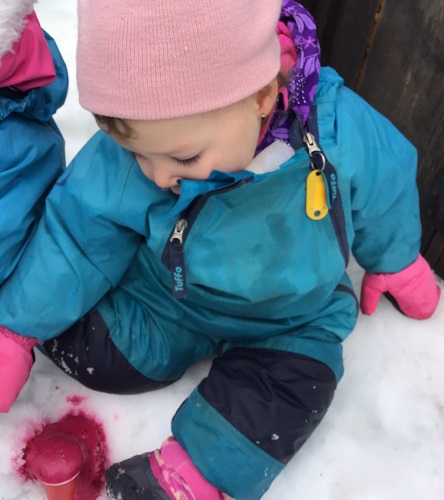 A toddler looking at the cup of pink foam