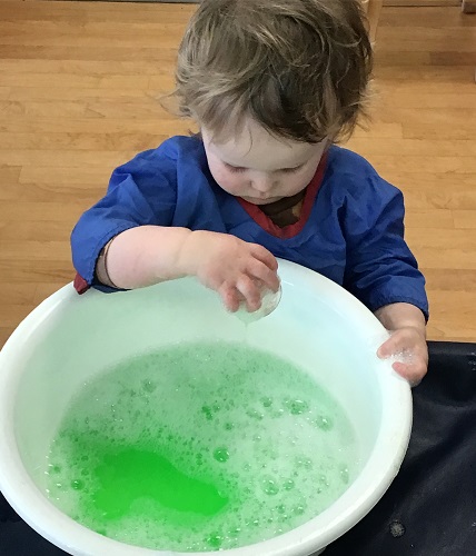 A child exploring with colourful water