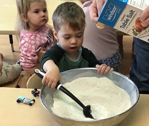 A child stirring flour in a big bowl